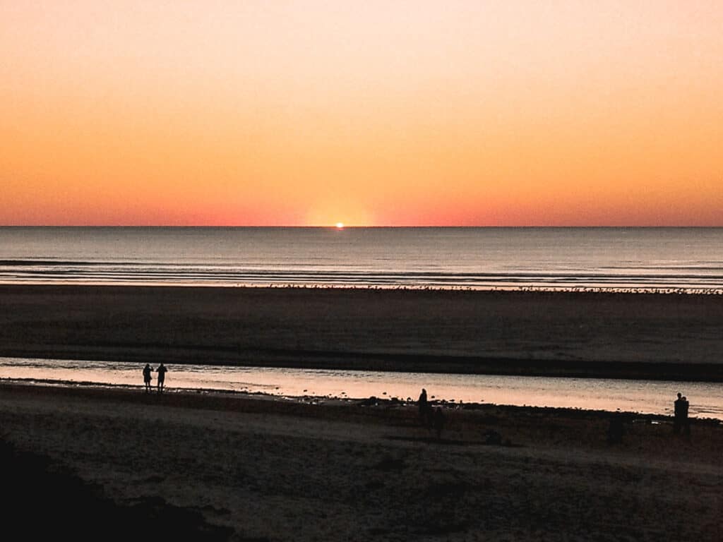 cannon beach at sunset. orange sky with sun just about to set over the horizon of the ocean