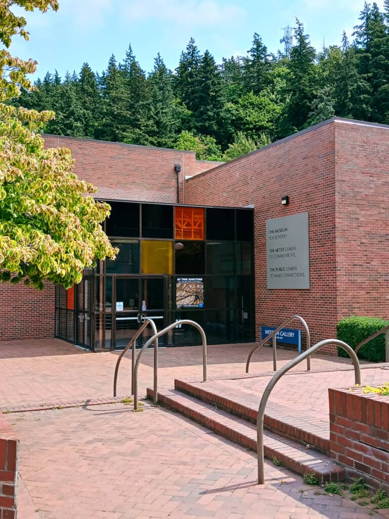 photo of the art gallery at WWU,red brick exterior, red paver plaza with evergreens and blue skies in the background