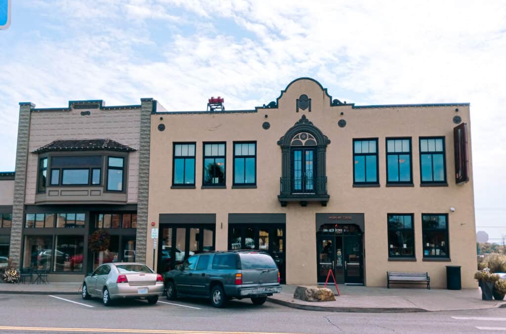 beige stucco building with small arch on roofline and ornate window with small balcony, jansen art center lynden wa