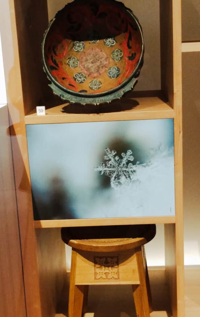wooden bowl with red interior painted with gold flowers and wooden stool with embossed design on a vertical shelf, nordic museum ballard