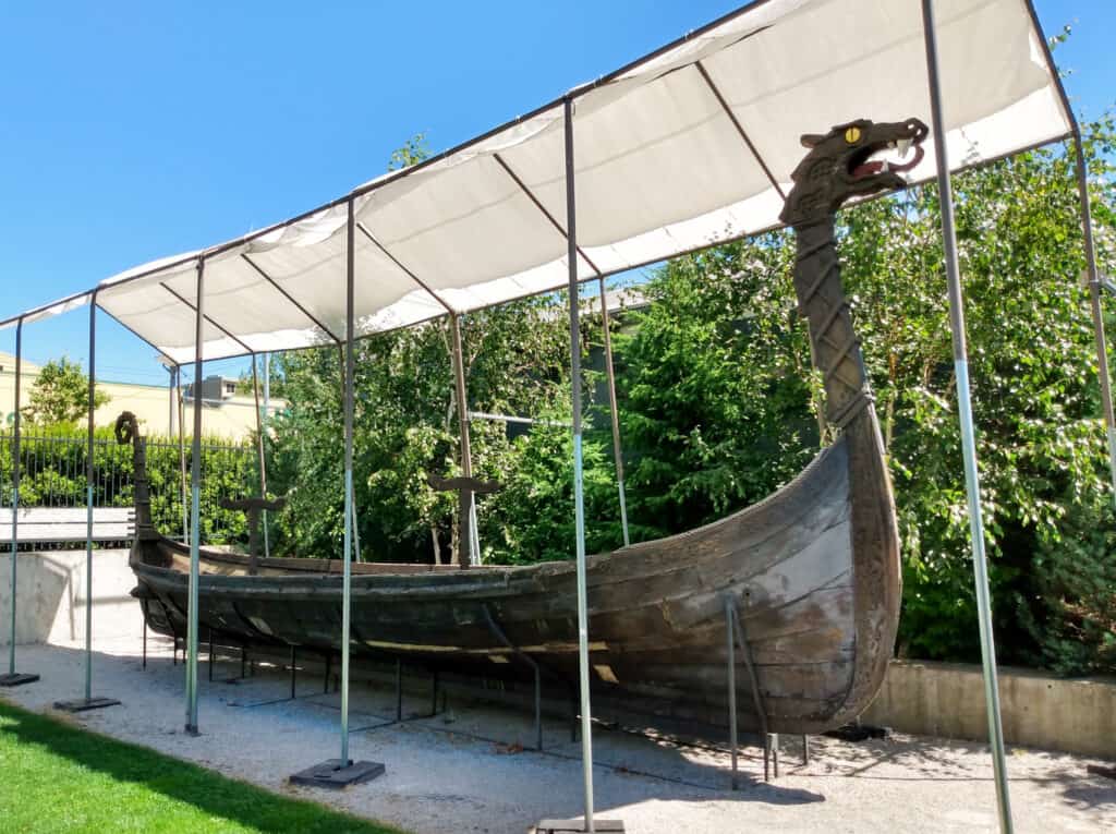 viking boat with dragon head at front under a white tent canopy outside, nordic museum ballard