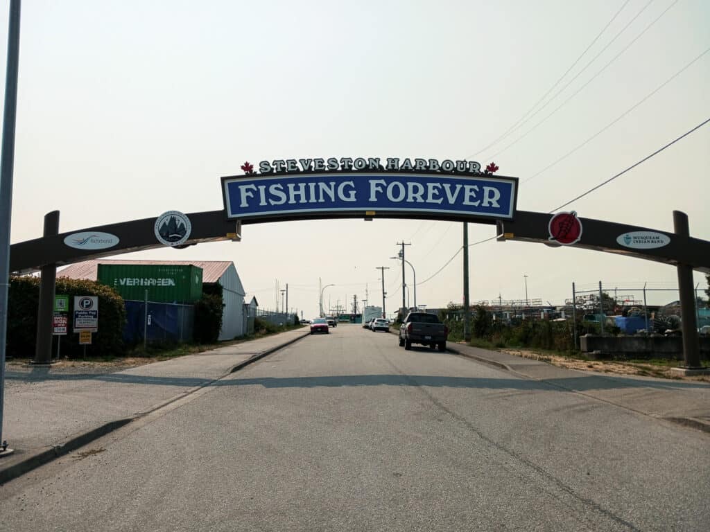 arched sign over roadway with text "steveston harbour fishing forever"