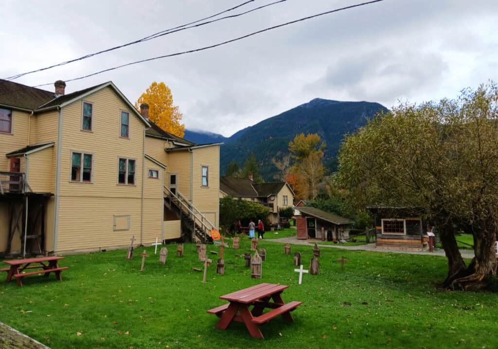 yellow historic three story building, faux cemetary and picnic table on a historic farmsite, Kilby, Harrison Mills