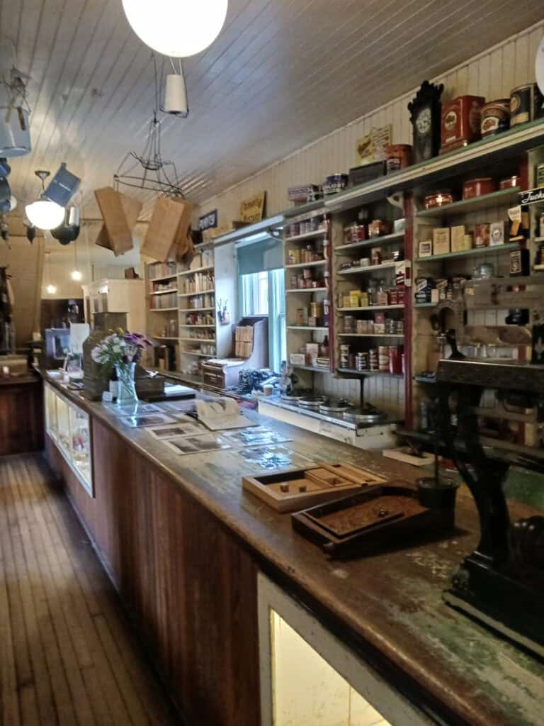 1920s replica of a general store with wooden counters and shelves lined with historic tins against the walls
