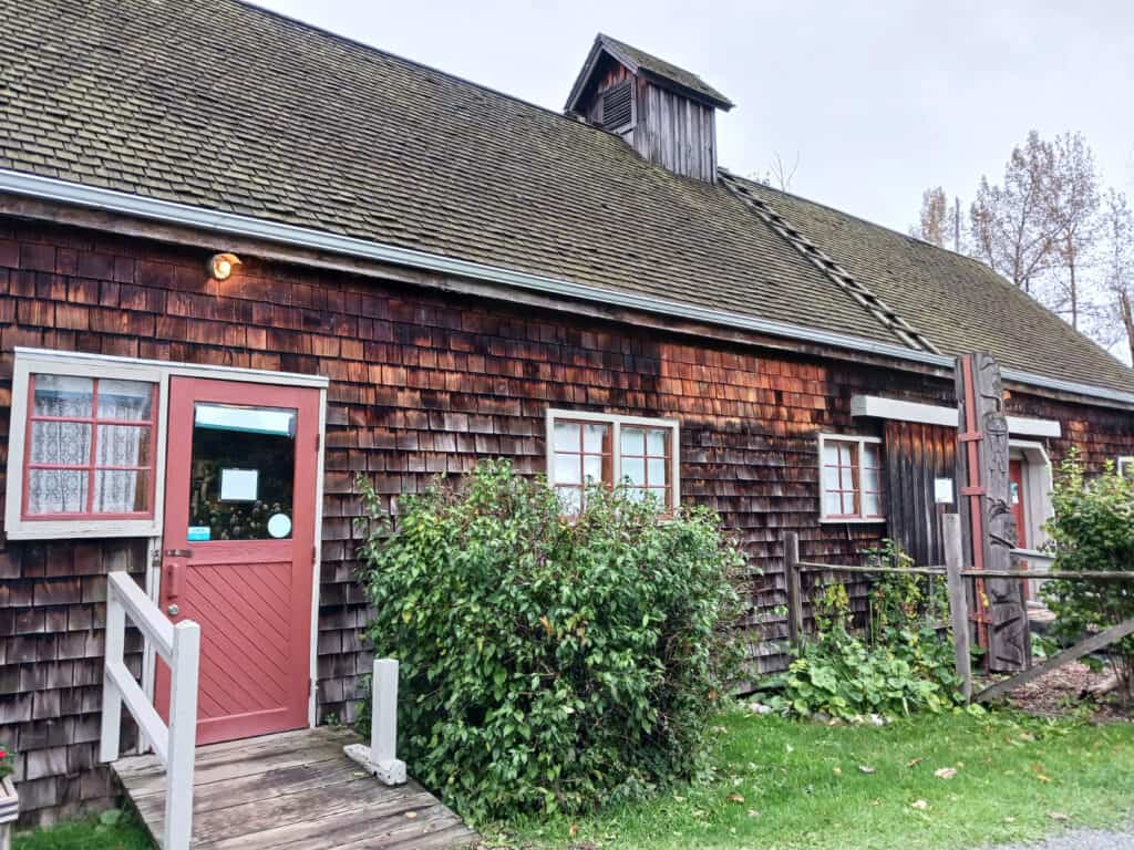 one story cedar shake sided building with red door